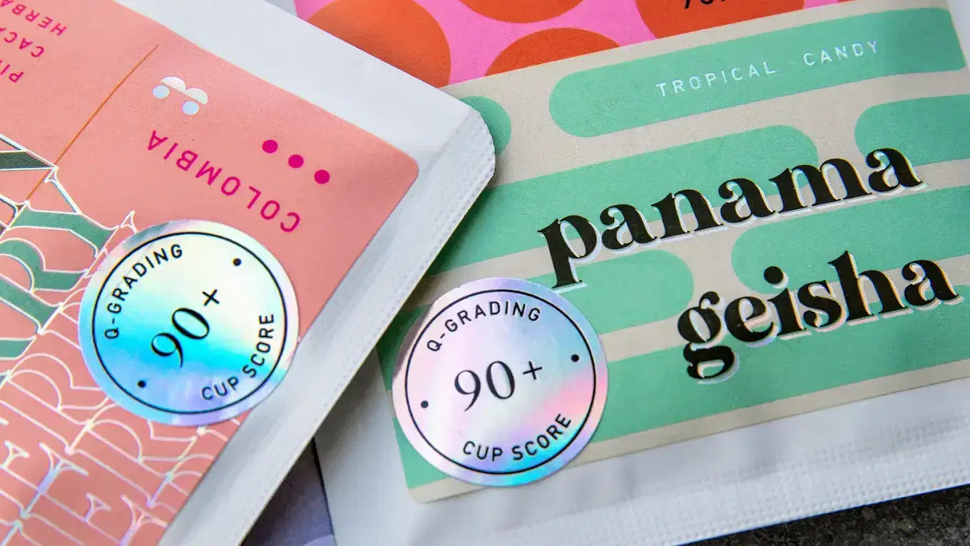 Colorful coffee packaging featuring Panama Geisha and Colombia varieties with 90+ cup score stickers.