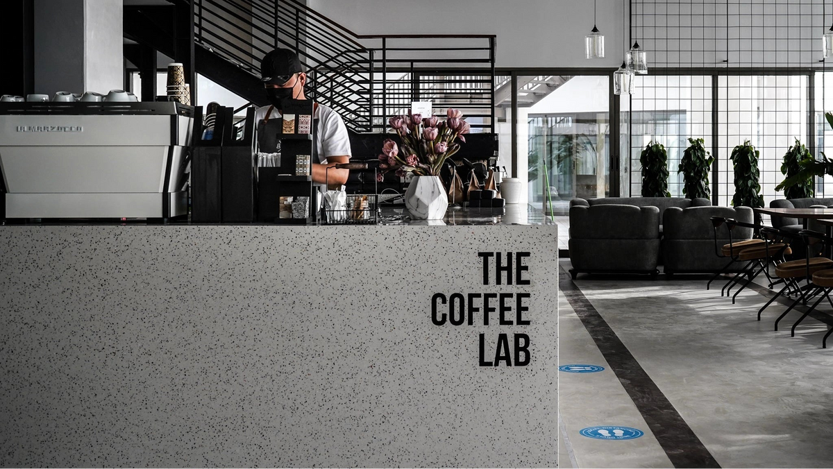 Person working behind a counter with 'The Coffee Lab' branding in a modern cafe setting.