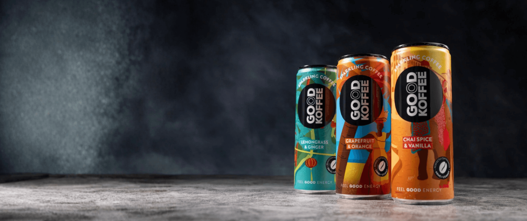 Three cans of Good Coffee on a wooden surface with a dark background