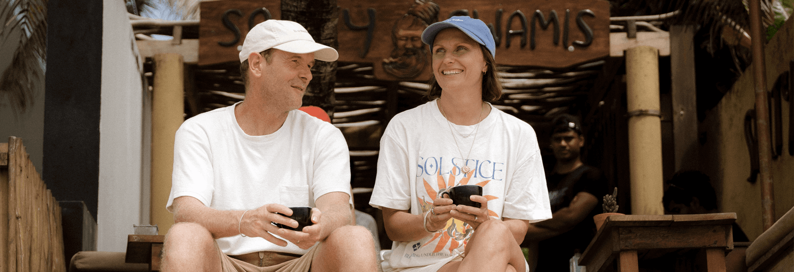 Couple enjoying drinks at a cafe in Dubai, surrounded by palm trees and vibrant decor.