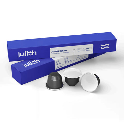 BlueJulith coffee capsule packaging with two blue boxes and three coffee capsules in front on a white background.