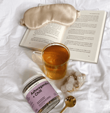 Ashwagandha + Chill Superfood Tea with a cup of tea, eye mask, a book, and crystals on a cozy blanket.