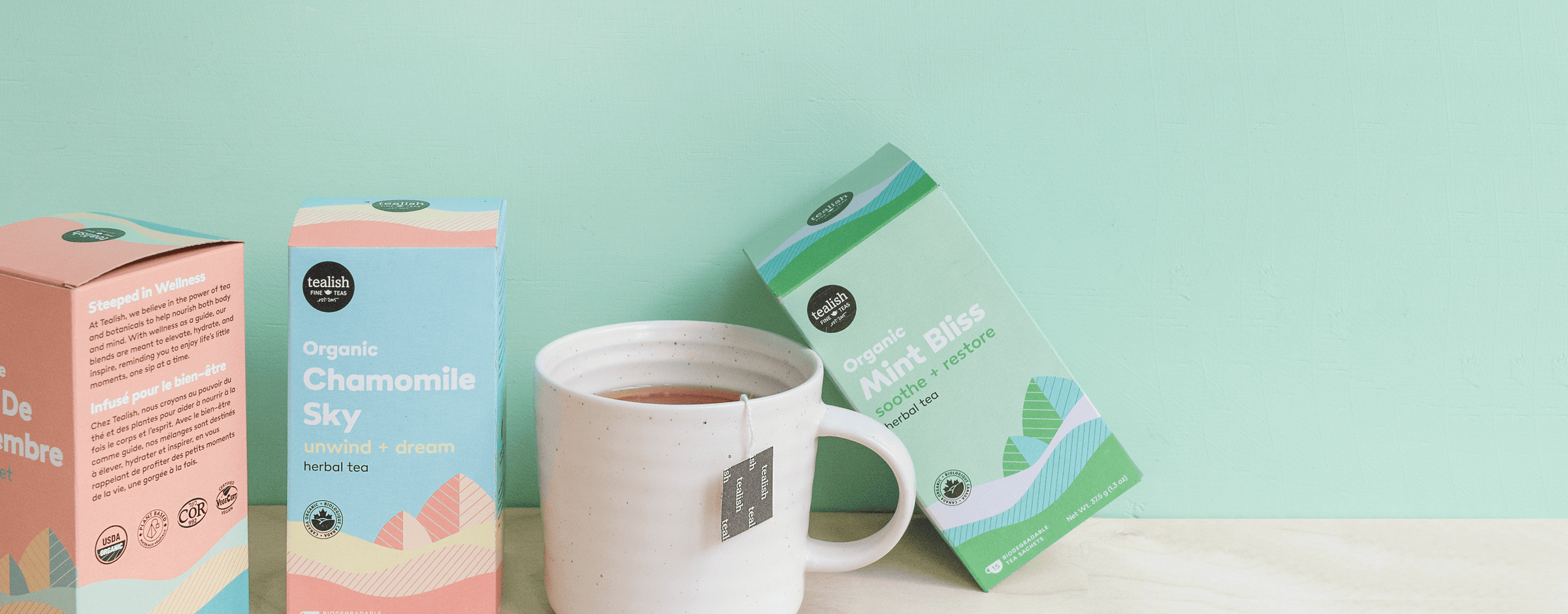 Organic chamomile and mint bliss tea boxes with a white mug on a mint green background