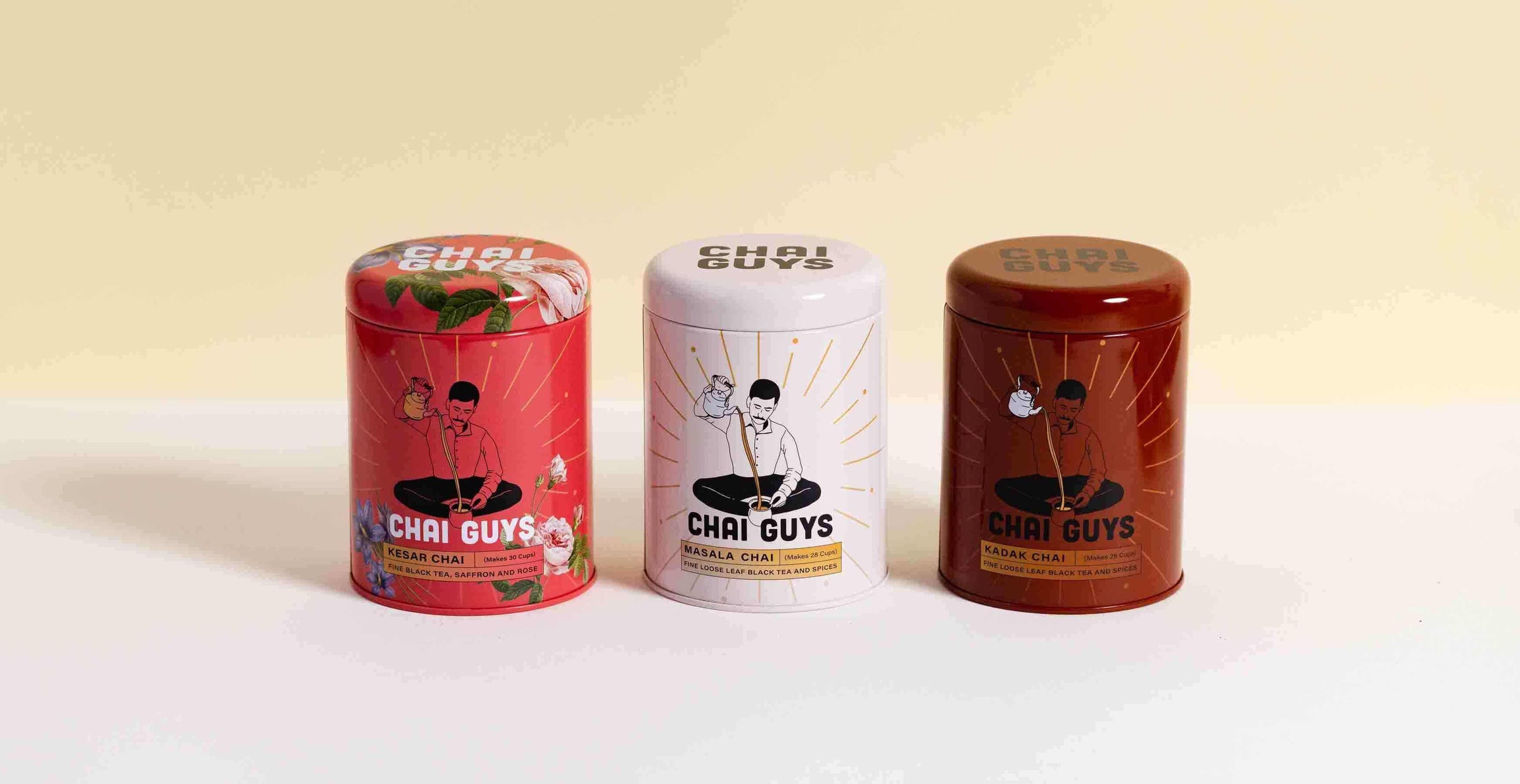 Three Chai Guys tea tins in red, white and brown packaging displayed on a clean studio background