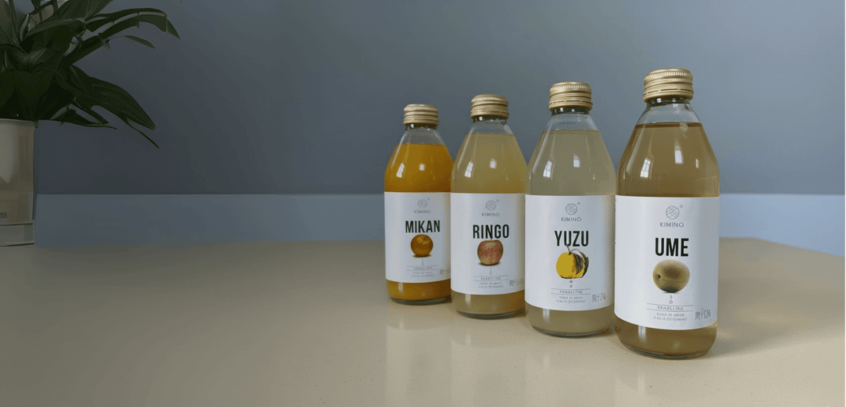 Four flavored beverages: Mikan, Ringo, Yuzu, and Ume, displayed with a simple backdrop and plant.