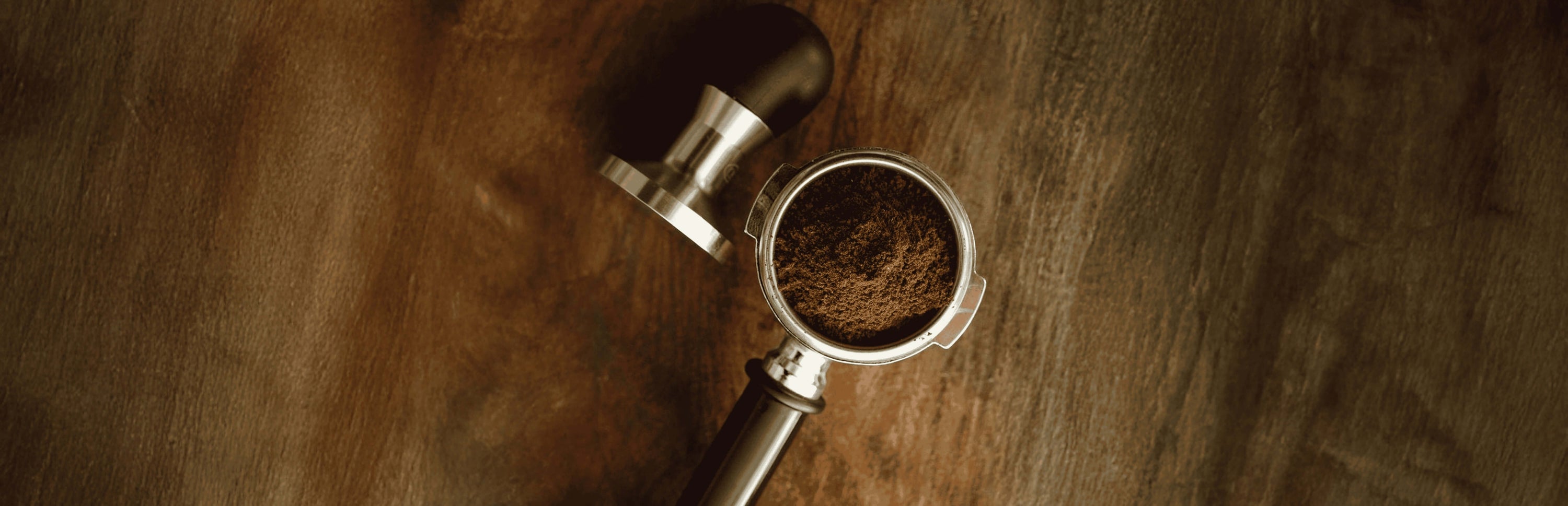 Freshly ground coffee in a portafilter on a wooden table, perfect for coffee lovers in Dubai, UAE.