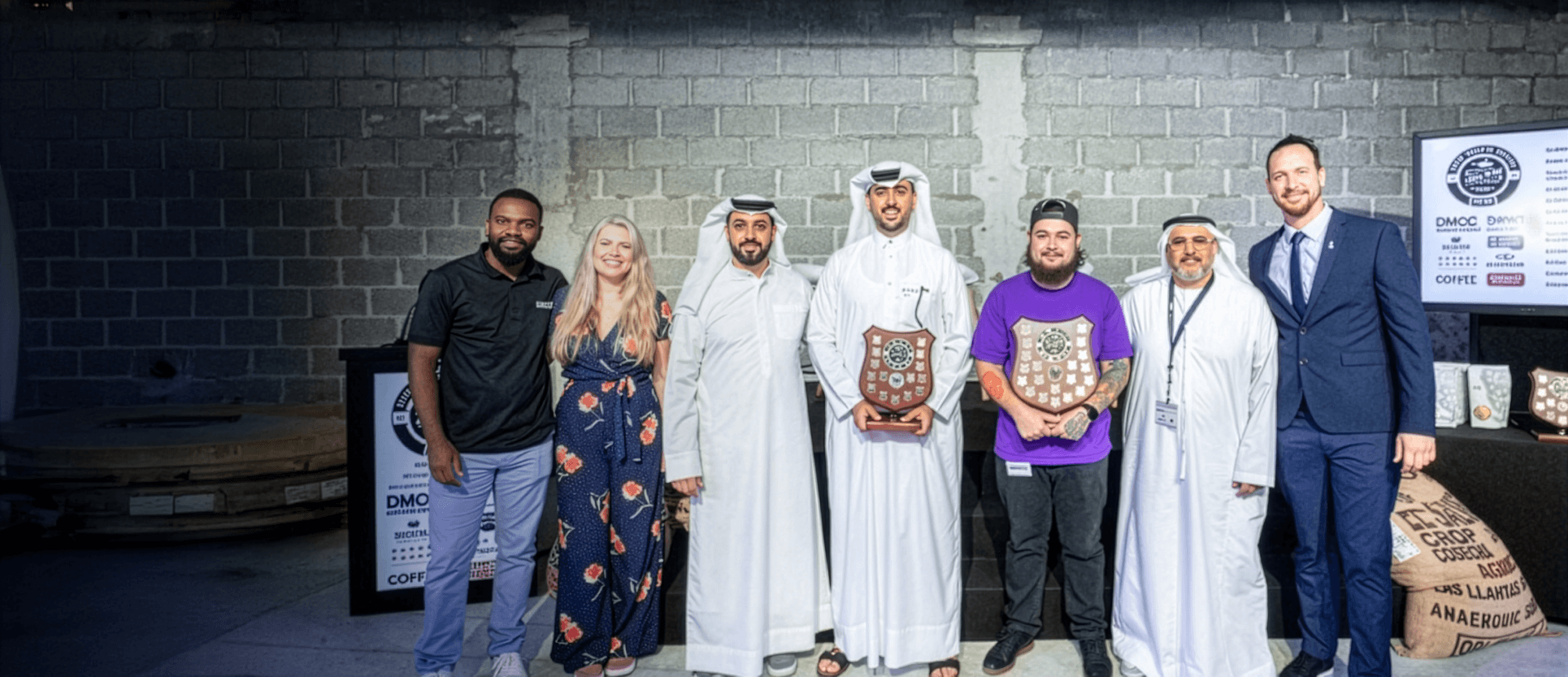 Group photo at an award ceremony with participants holding trophies, celebrating achievements in coffee industry in Dubai.