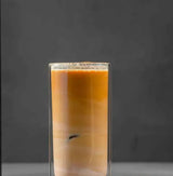 Delicious Brazil Vale Dourado coffee in a clear glass, showcasing its rich, velvety texture and warm tones.