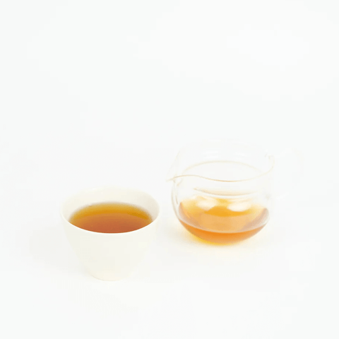 Chamomile Hojicha in a white cup and glass pitcher showcasing its warm, inviting color.