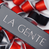 Colombia Caturra Capsules packaging with vibrant red and black coffee pods background.