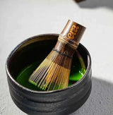Era Dark Bamboo Chasen — Matcha Whisk in a bowl of vibrant green matcha.