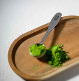 Era Matcha Scoop measuring matcha powder on a wooden tray, showcasing its sleek design and precision for matcha preparation.