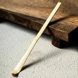 Era White Bamboo Chashaku — Matcha Spoon resting on a wooden surface, showcasing its handcrafted design.