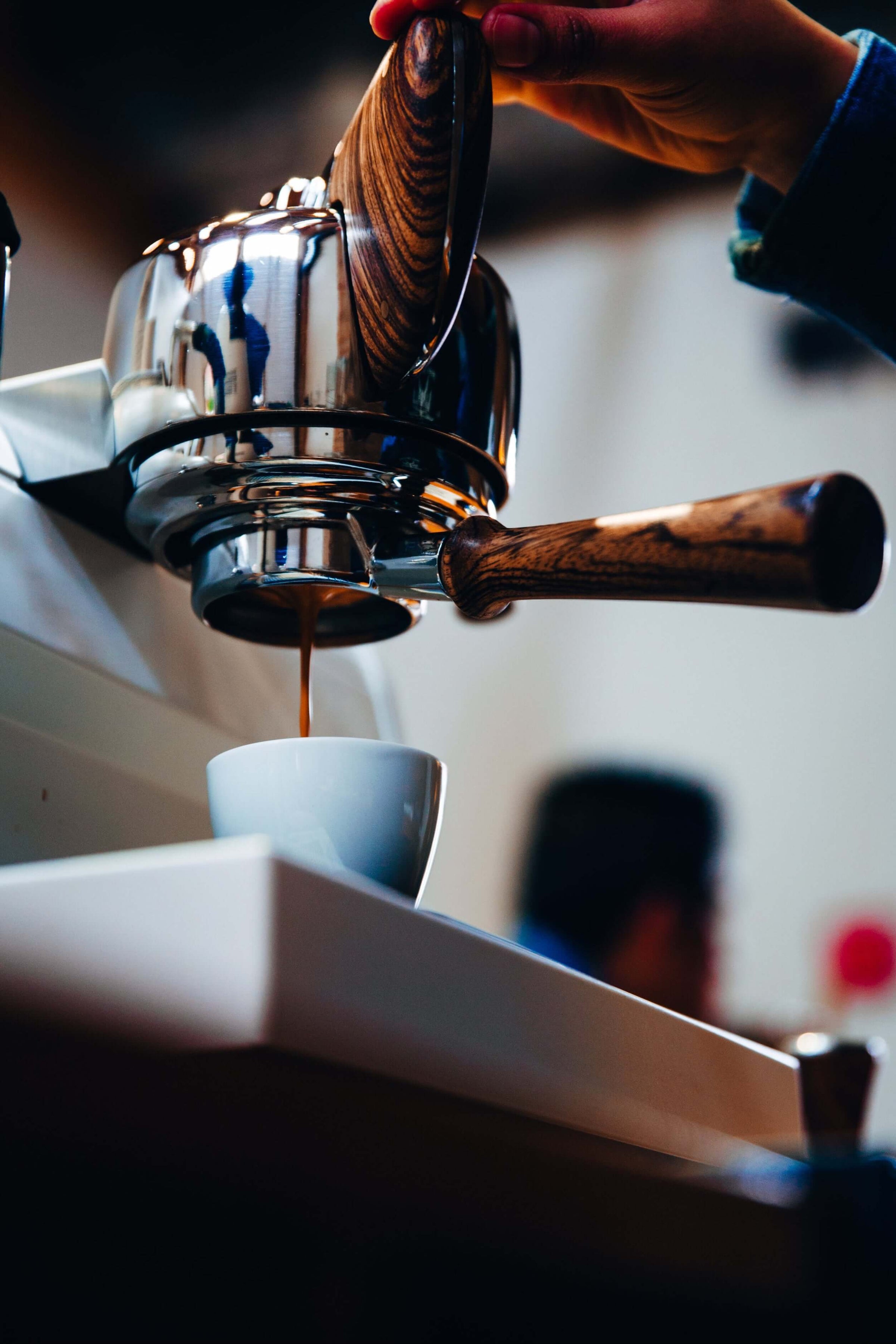 Barista brewing espresso with a stylish coffee machine, showcasing a rich pour into a small cup.