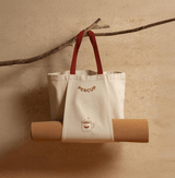 Natural color Tote Bag with red straps hanging, featuring a cup illustration and a cork yoga mat.