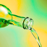 Pistachio Syrup pouring from a green glass bottle, showcasing its vibrant color and natural ingredients.