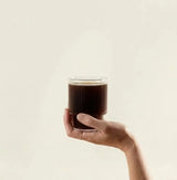 Reishi Mushroom Powder in a glass held by hand, calming mushroom drink for relaxation and sleep support