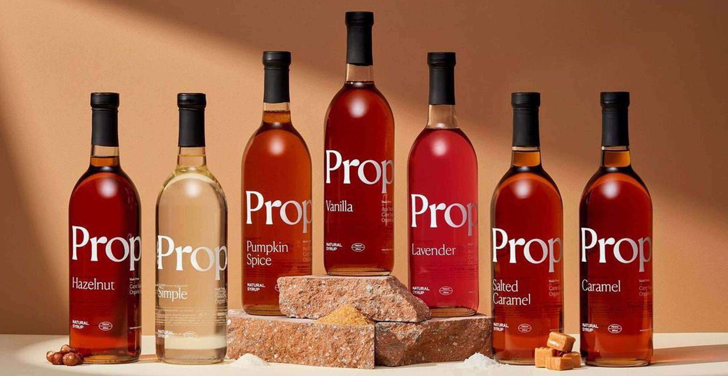 Botellas de jarabe Pro con sabores vainilla, avellana, caramelo y especias, exhibidas sobre bloques de madera