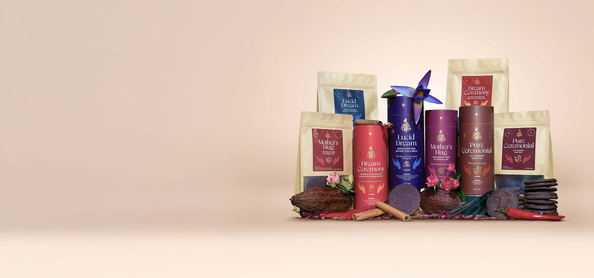 An assortment of Seeds of Power cacao products, including cylindrical and pouch packaging of Lucid Dream, Dream Ceremony, Mother’s Hug, and Pure Ceremonial, surrounded by cacao beans, chocolate pieces, spices, and flowers.