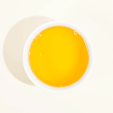 A cup of Single Cultivar Organic Koshun Japanese Oolong tea with a bright yellow hue.