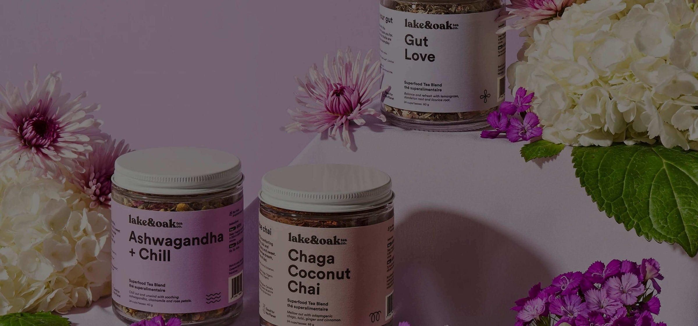 Lake&Oak wellness mushroom and adaptogen supplement jars with flowers on a soft pink background